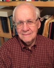 Photo of retired physician Dr. Thomas Gaffney sitting in front of a full bookshelf.