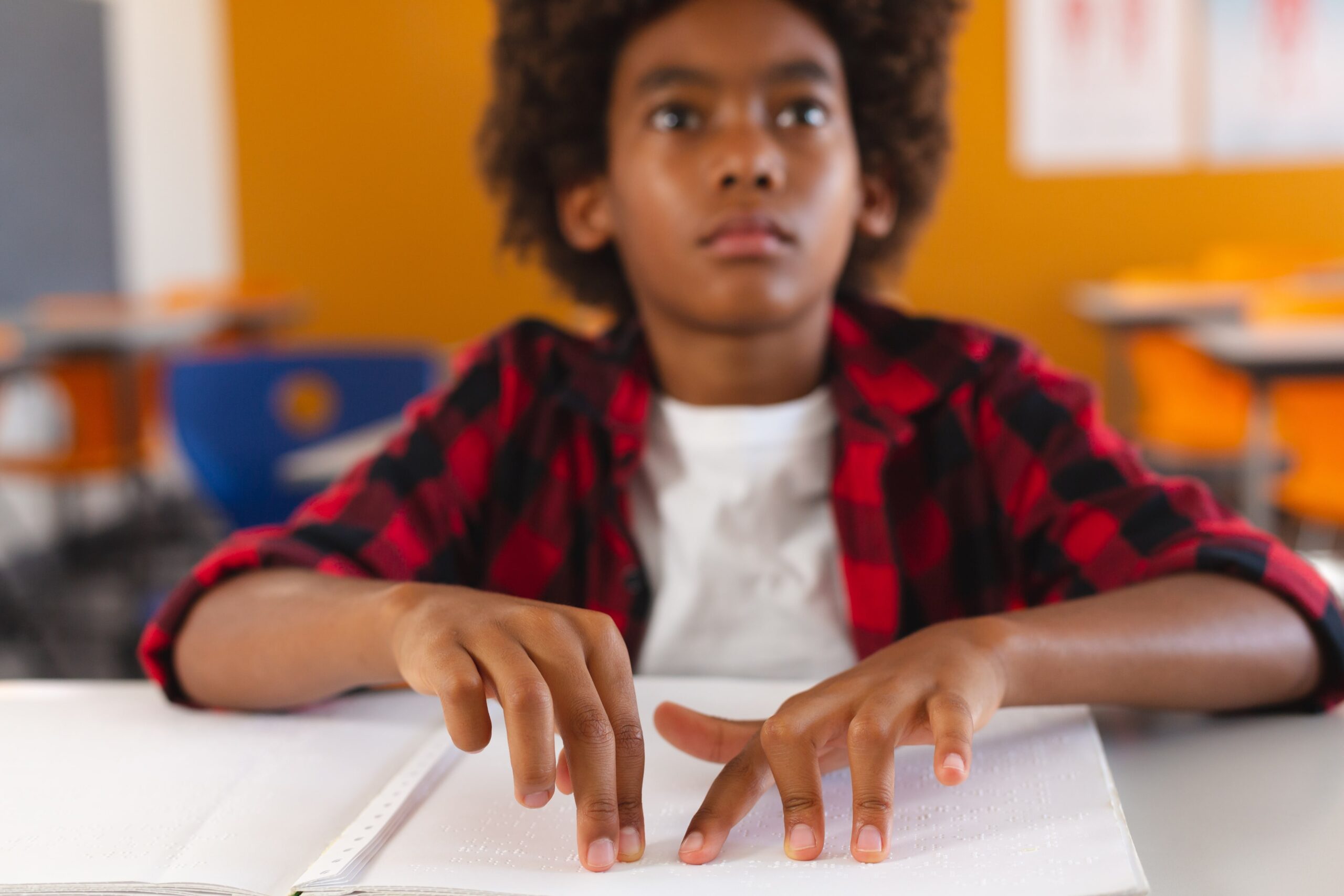 A young boy reading braille on a book